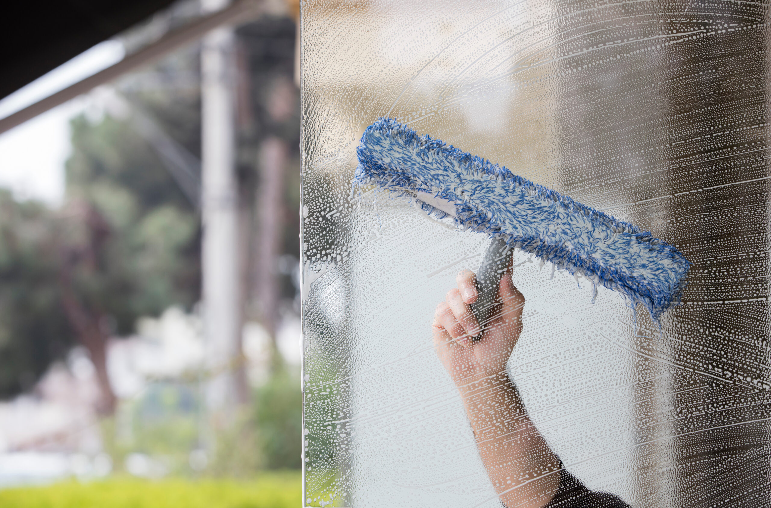 A person cleaning windows with a blue mop.